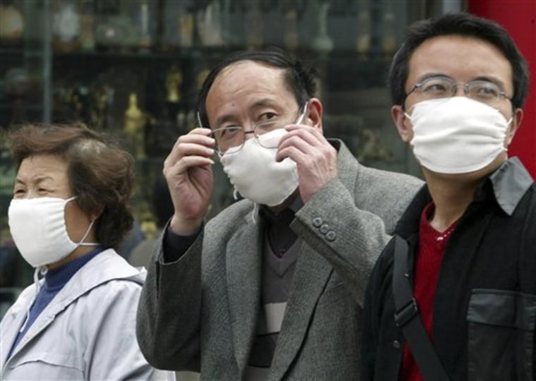 In this Monday, April 21, 2003, file photo, a Chinese man wearing a mask removes his glasses while walking with others in downtown Beijing, China. A genetic variant commonly found in Chinese people may help explain why some patients got seriously ill with swine flu, a discovery scientists say could help pinpoint why flu viruses hit some populations particularly hard and change how they're treated.